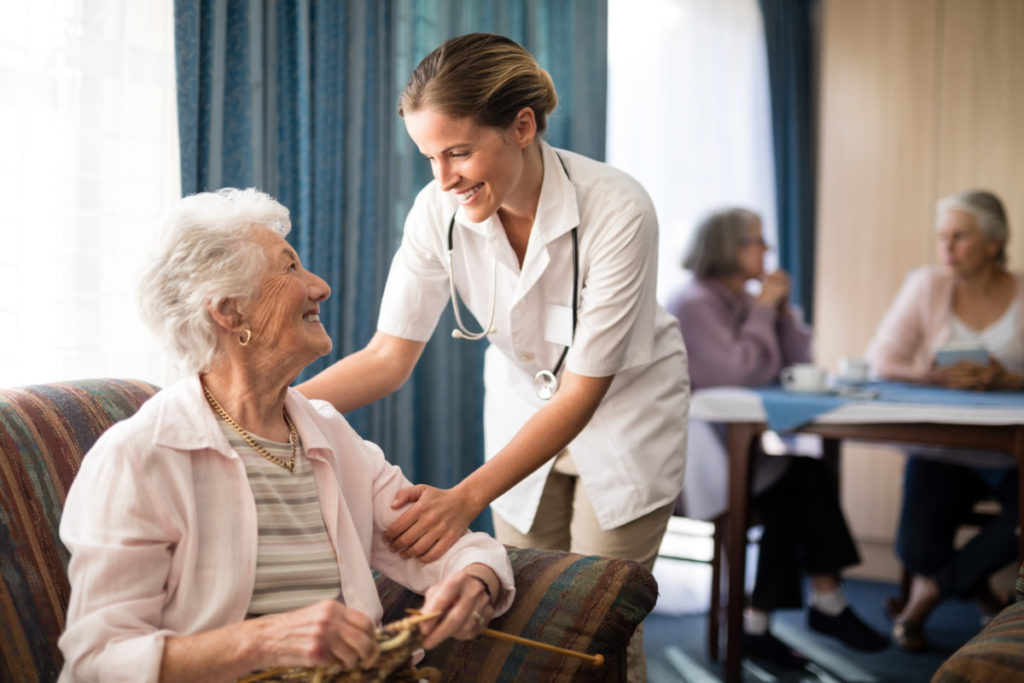 Smiling female doctor talking with senior woman at retirement home Aide Soignante sourie à une personne agée